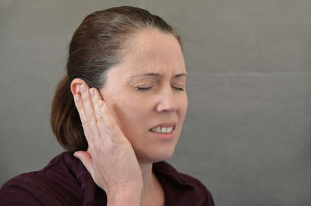 Adult woman (female age 30-40) suffering from pain in her ears.
