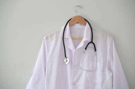 Doctor coat in coat hanger with professional modern stethoscope  hanged on clinic office wall.の写真素材