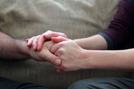 Supportive wife holding the hand of her upset husband .Couple relationship issues concept.の写真素材