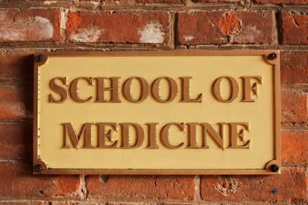 School of Medicine sign hanged on an old brick wall.