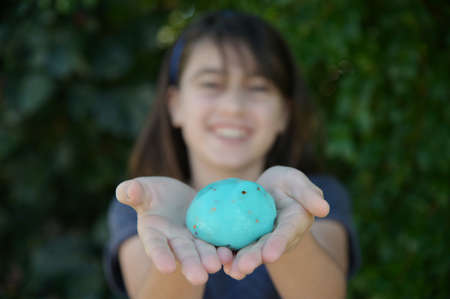 Happy teenager girl (female age 11-12) smiling while holding slime toy outdoors. Real people. Copy spaceの写真素材