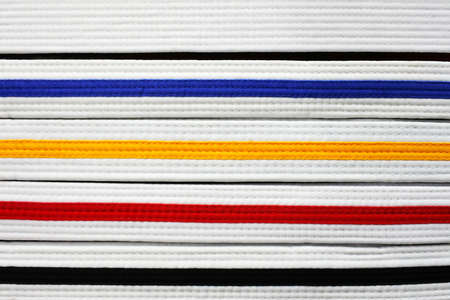 Coloured East Asian martial arts belt ranks: Black, red , yellow, blue and white abstract background and texture.の写真素材