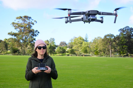 PERTH, WA - AUG 17 2021:Woman flying a DJI Mavic 2 drone in the park. The Mavic is a series of...