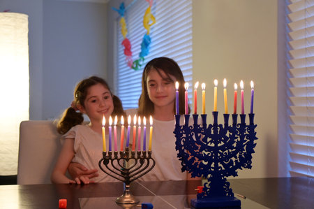 Two sisters looking at candelabrum (hanukkiah) on the eight day of Hanukkah Jewish holiday festival commemorate the rededication of Jerusalem Second Temple in the 2nd century BCE.の写真素材