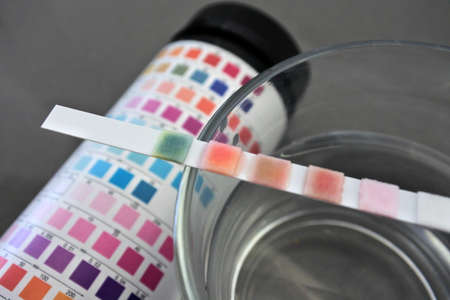 Close up of drinking water test kit on glass cup filled with tap water.