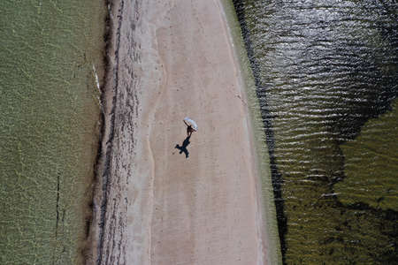 Aerial drone view of Australian woman walking on empty narrow sand bar in Shark Bay, Western Australia.の写真素材