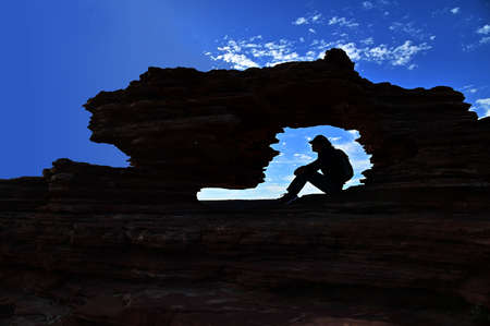 Silhouette of Australian female hiker resting inside Nature's Window at Murchison Gorge and river view of Kalbarri National Park Western Australiaの写真素材