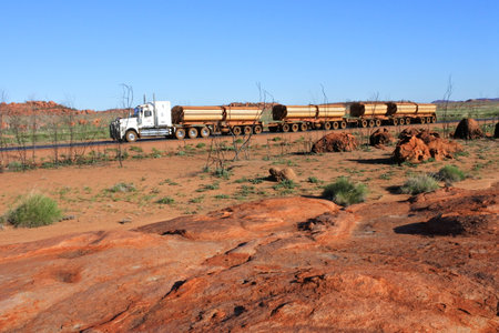 PORT HEDLAND, WA - JUNE 20 2022: Four-trailer road train driving on Great Northern Highway and...