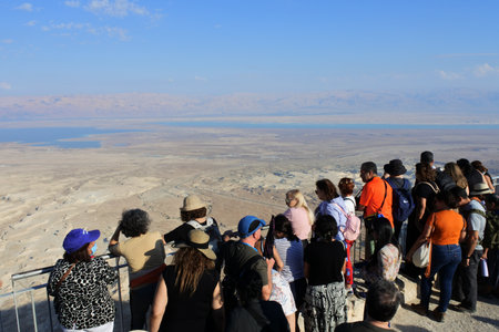 MASADA, ISR - NOV 10 2022:Group of tourist looking at landscape view of the Dead sea and Jordan from Masada ancient natural fortress in Holy land Israel.The site attracts around 750,000 visitors a year.のeditorial素材