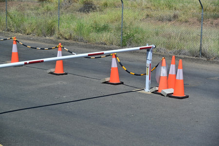 Closed traffic gate and cones on a road background.