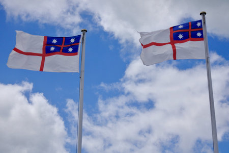 Two flags of the United Tribes of New Zealand (1834) flying under blue sky with white clouds.の写真素材