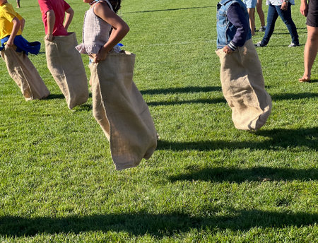 Unrecognizable children traditional potato sack race a competitive game in which participants place both of their legs inside a potato sack hop forward from a starting point toward a finish line.の写真素材