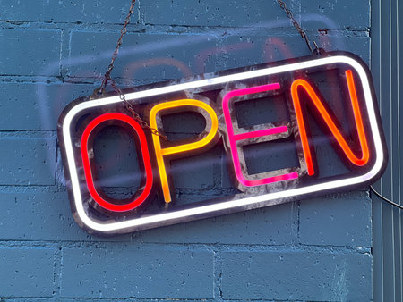 Colorful neon open sign on a brick wall
