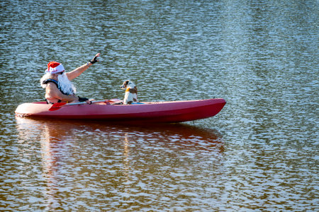 PORT MACQUARIE - DES 01 2025:Santa Claus in kayak wave hello. Santa Claus is  a legendary figure who delivers gifts at Christmas based on a 4th-century bishop named St. Nicholas.のeditorial素材