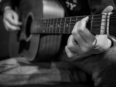 Practice playing the acoustic guitar. Hands playing guitar and picking chords.