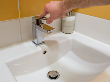 Running water from a square faucet in a modern bathroom.の写真素材