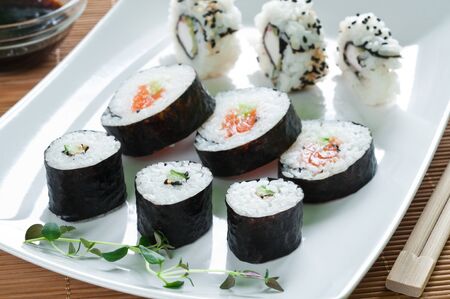 Selection of Japanese sushi arranged with thyme on white plateの写真素材