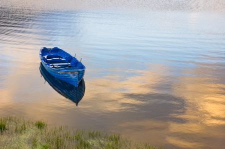 Boat on calm water with clouds reflectionの写真素材