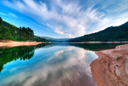 Lake in Da Peneda Geres Park with blue sky and clouds reflected in waterの写真素材
