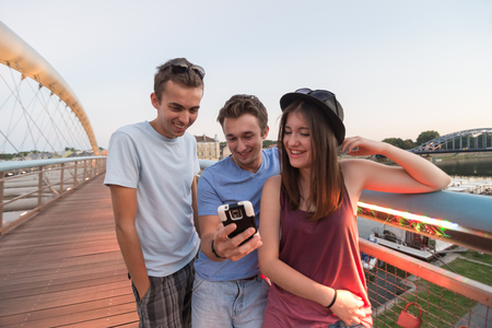 A group of young adult friends smiling and taking selfieの写真素材