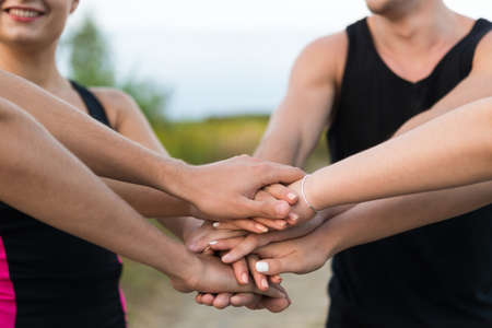 Team of young adults putting hands together outdoors - workout motivation conceptの写真素材