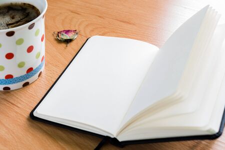 Close up of cup of coffee and notebook on a wooden table with copy spaceの写真素材