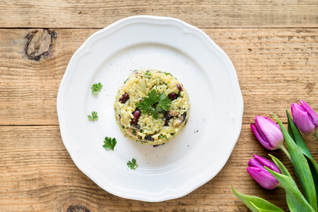 Top view of risotto (pilaf) with jasmine rice, red beans and vegetables on white plate on wooden rustic tableの写真素材