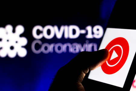 April 8, 2020, Brazil. In this photo illustration the YouTube Play logo seen displayed on a smartphone with a computer model of the COVID-19 coronavirus in the background.のeditorial素材