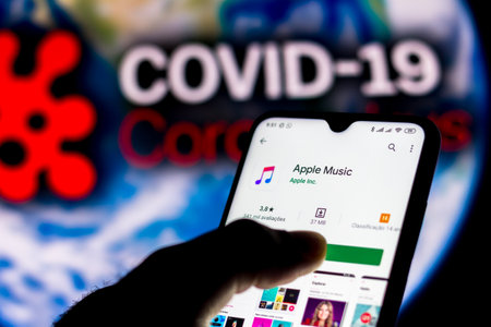 April 8, 2020, Brazil. In this photo illustration the Apple Music logo seen displayed on a smartphone with a computer model of the COVID-19 coronavirus in the background.のeditorial素材