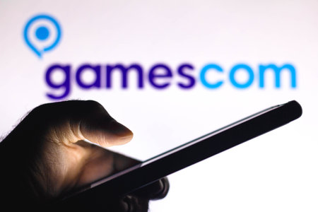 January 20, 2021, Brazil. In this photo illustration the Gamescom logo seen in the background of a silhouette hand holding a mobile phoneのeditorial素材