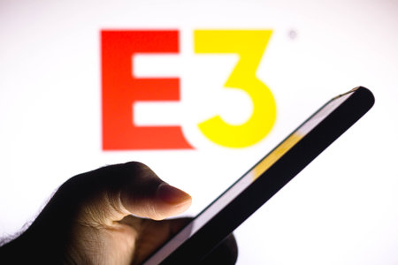 January 20, 2021, Brazil. In this photo illustration the Gamescom logo seen in the background of a silhouette hand holding a mobile phoneのeditorial素材