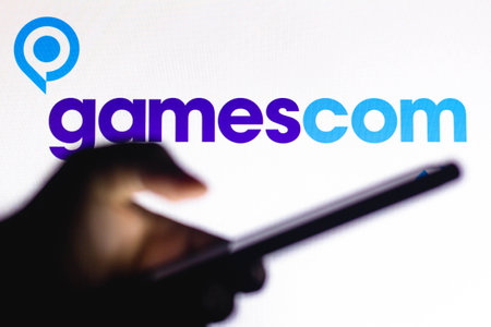 January 20, 2021, Brazil. In this photo illustration the Gamescom logo seen in the background of a silhouette hand holding a mobile phoneのeditorial素材