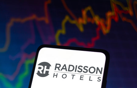 December 8, 2021, Brazil. In this photo illustration the Westin Hotels and Resorts logo displayed on a smartphone and in the background a stock market graphのeditorial素材
