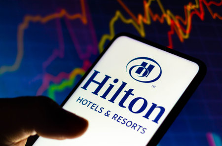 December 8, 2021, Brazil. In this photo illustration the Westin Hotels and Resorts logo displayed on a smartphone and in the background a stock market graphのeditorial素材