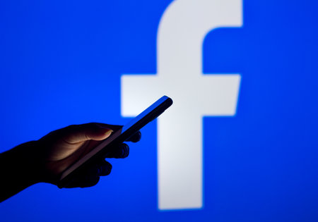 March 16, 2022, Brazil. In this photo illustration, a woman holds a smartphone with the Facebook...