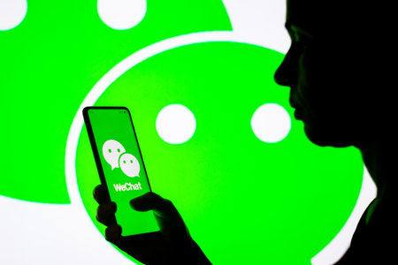 March 28, 2022, Brazil. In this photo illustration, a woman's silhouette holds a smartphone with the Discord logo displayed on the screen and in the backgroundのeditorial素材