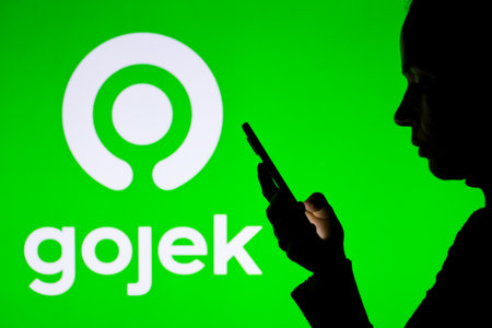 April 1, 2022, Brazil. In this photo illustration, a woman's silhouette holds a smartphone with the Gojek displayed on the screenのeditorial素材