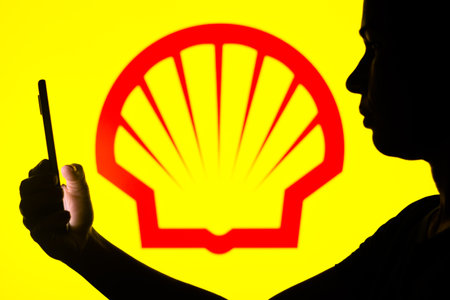 April 4, 2022, Brazil. In this photo illustration, a woman's silhouette holds a smartphone with the Chevron  displayed on the screenのeditorial素材