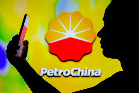 April 4, 2022, Brazil. In this photo illustration, a woman's silhouette holds a smartphone with the Chevron  displayed on the screenのeditorial素材