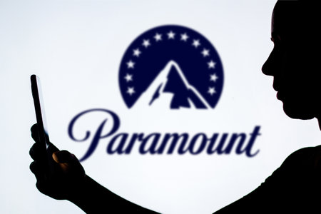 December 9, 2023, Brazil. In this photo illustration, a woman's silhouette holds a smartphone with the Paramount Global logo in the backgroundのeditorial素材
