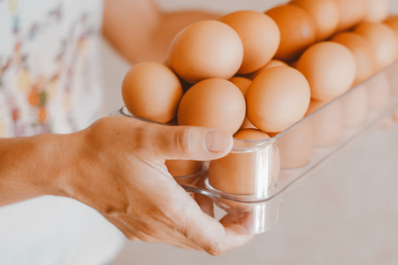 Close up of a woman holding a tray of free-range red eggs. The egg has nutrients with antioxidant action such as carotenoids, vitamin A and E, folic acid, zinc, magnesium and seleniumの写真素材
