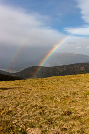 Double rainbow with forest and brown mountains and forest in the backgroundの写真素材