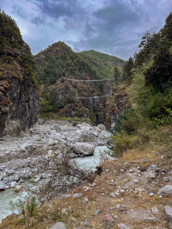 Cold water river between mountains with two hanging bridges in the background