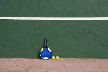Two yellow tennis balls and a racket near the tennis wallの写真素材