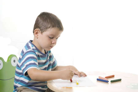A adorable kid painting the paper on the table ( isolated on white )