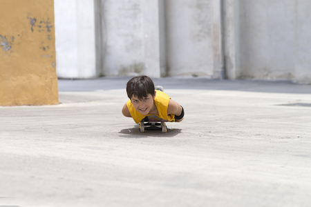 Young smiling boy on a skateboard while looking camera on a sunny dayの写真素材