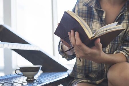Young woman with a ponytail sitting on a staircase while using a notebook next to a window