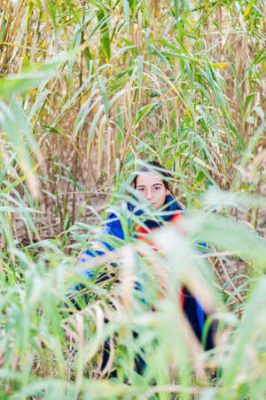 Young woman hiding behind a bush in the woodsの写真素材