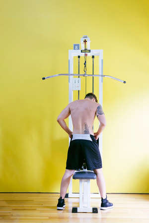 Fit man on lat pull down machine at the health club. Work out on Pull down Weight Machine