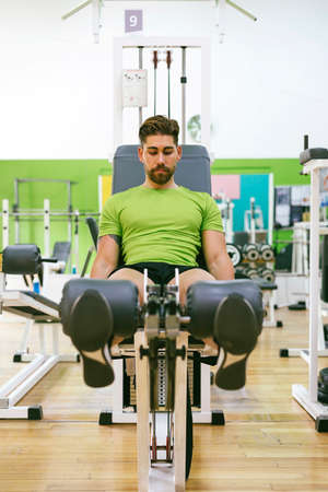 Young sportsman almost shouting when doing leg extension with heavy weight